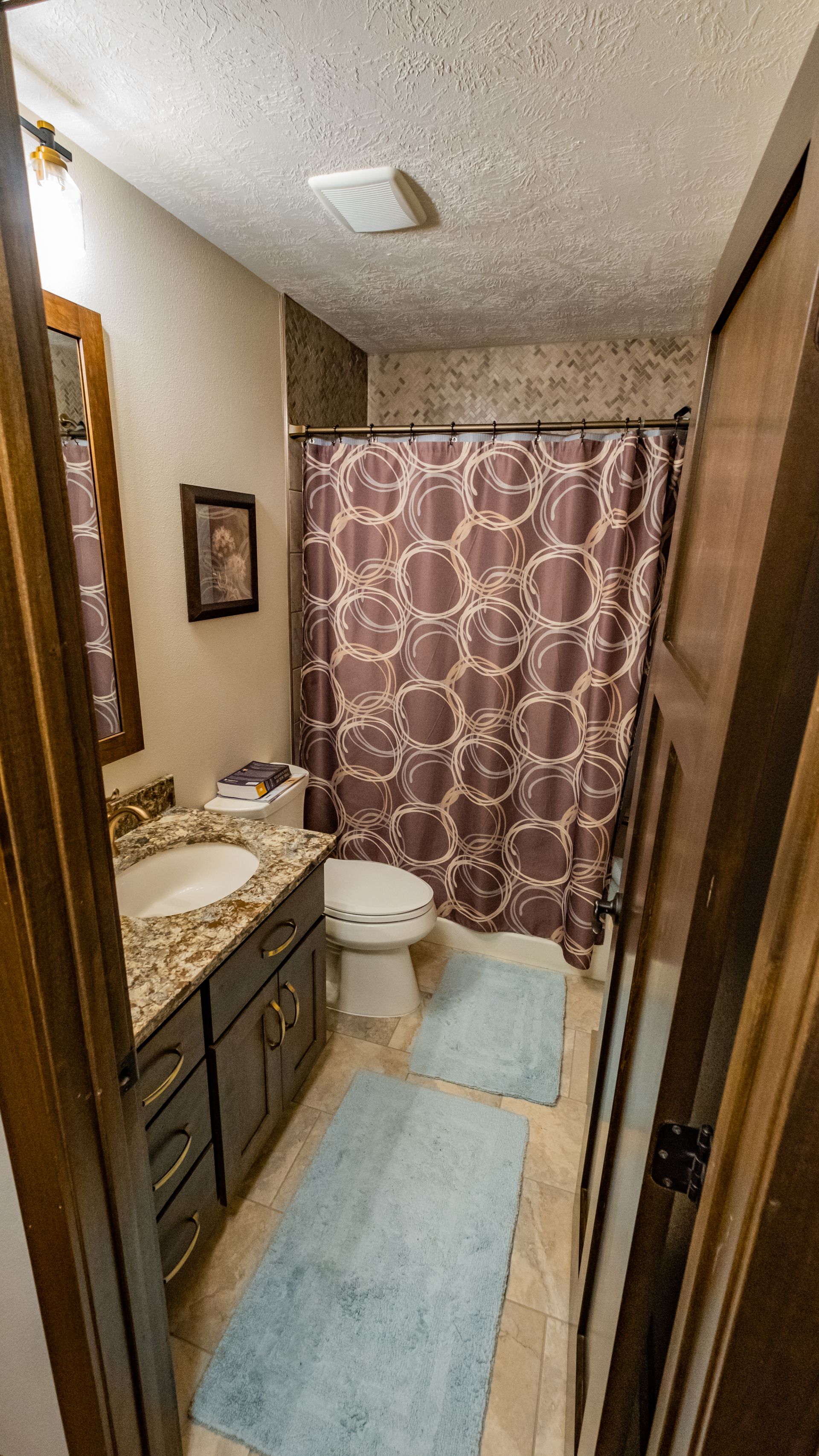 A bathroom with a toilet, sink, and shower curtain.