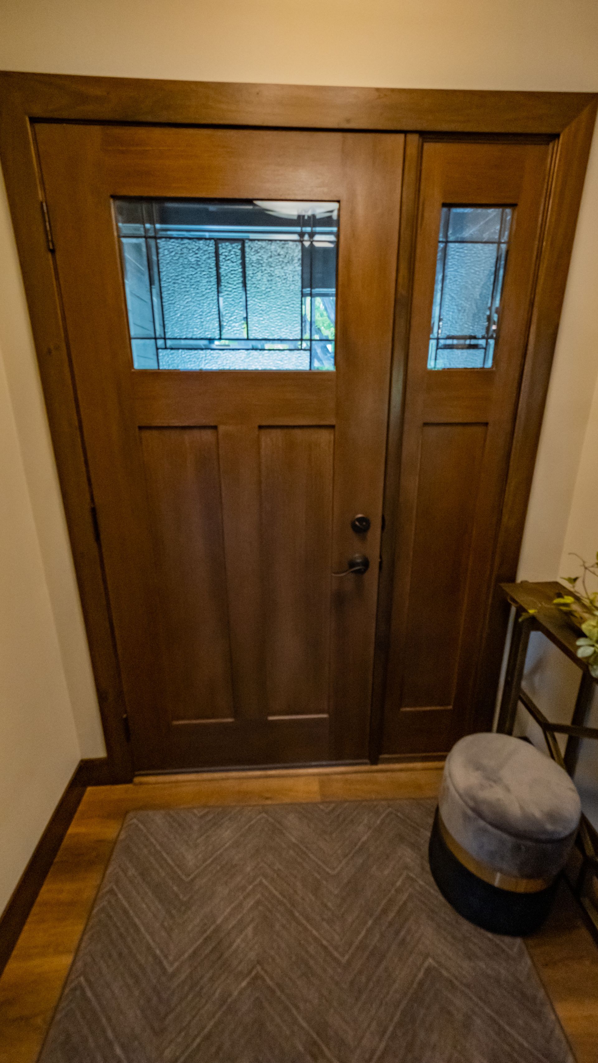A wooden door with a stained glass window in a hallway.