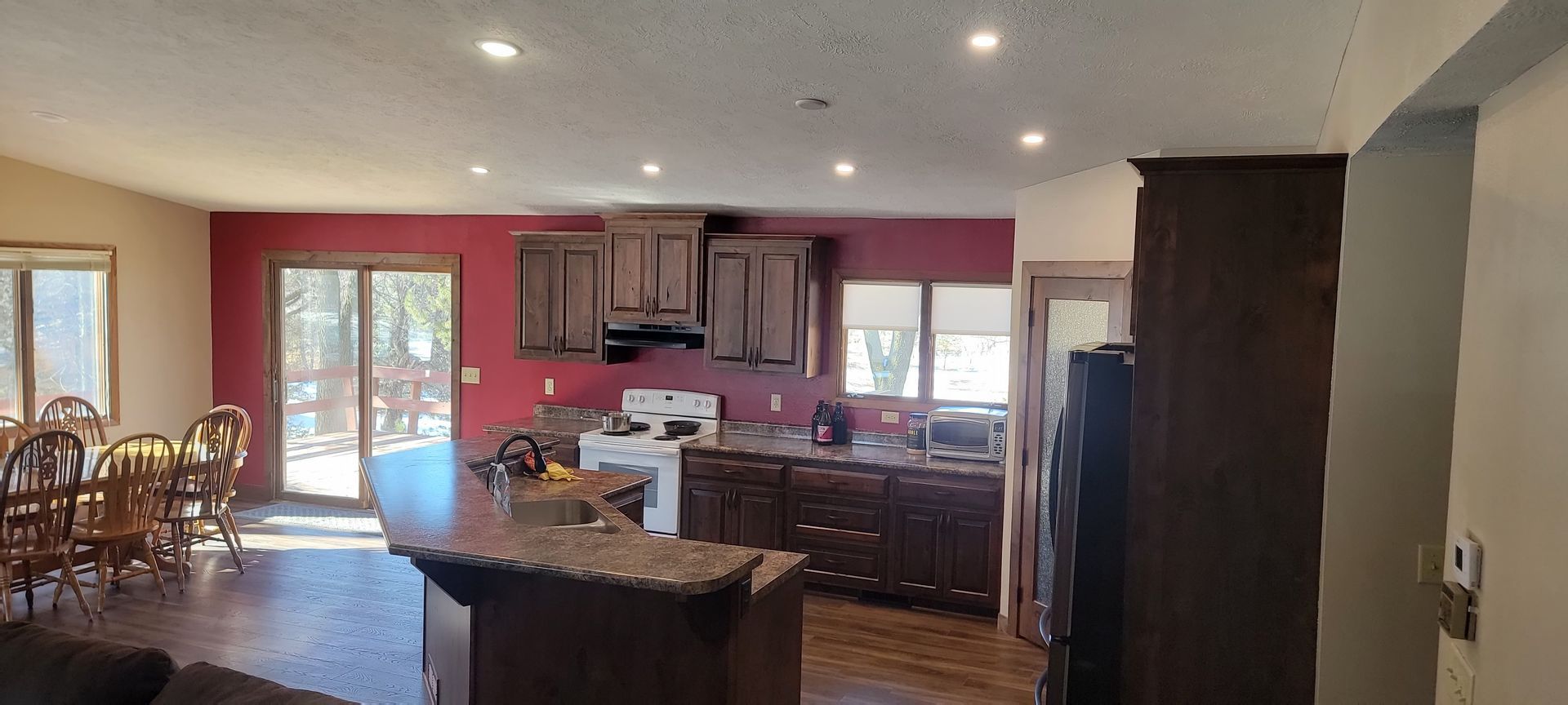A kitchen and dining room in a house with a red wall.