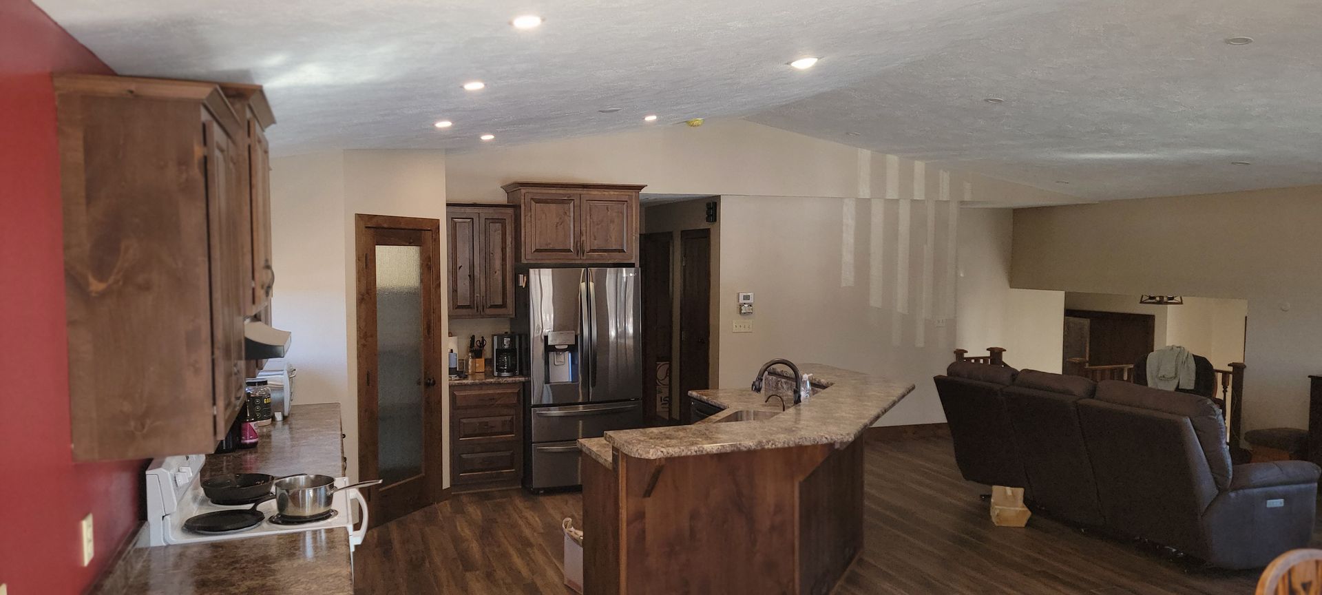 A kitchen and living room in a house with a couch and a refrigerator.