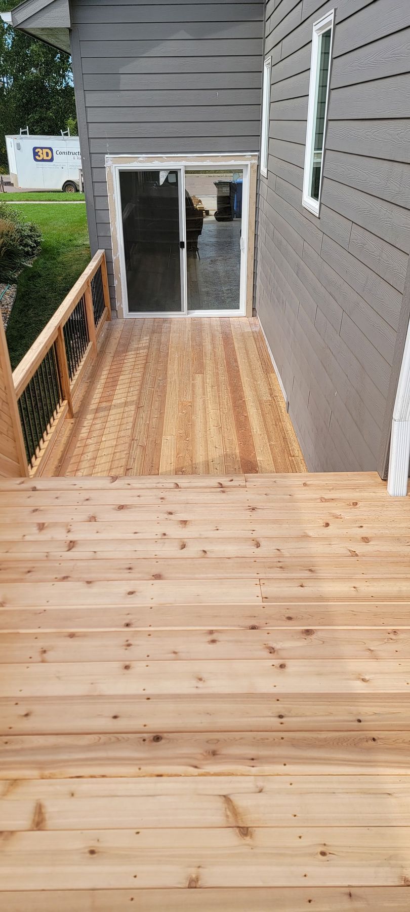 A wooden deck next to a house with a sliding glass door.