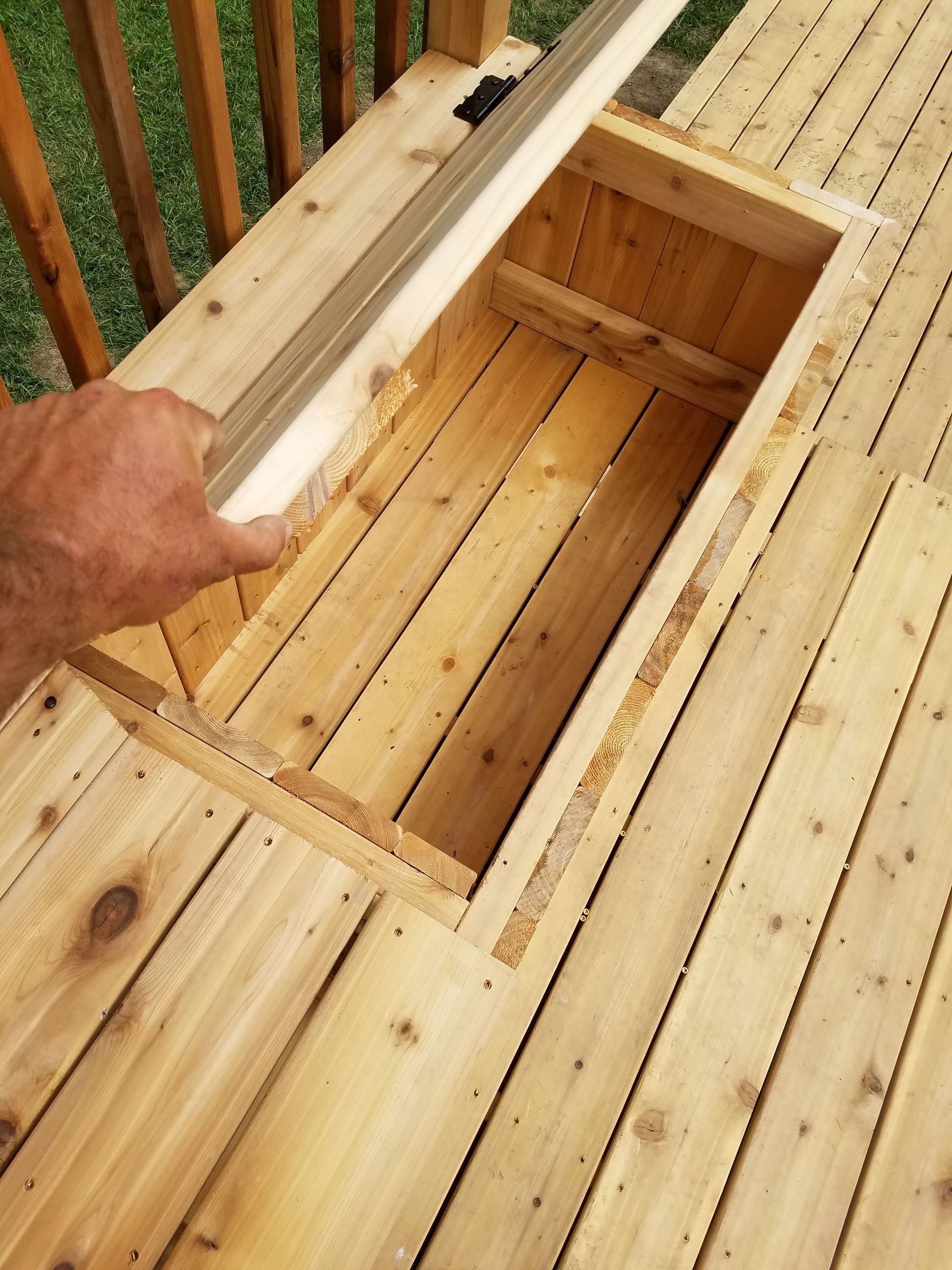 A person is opening a wooden box on a deck