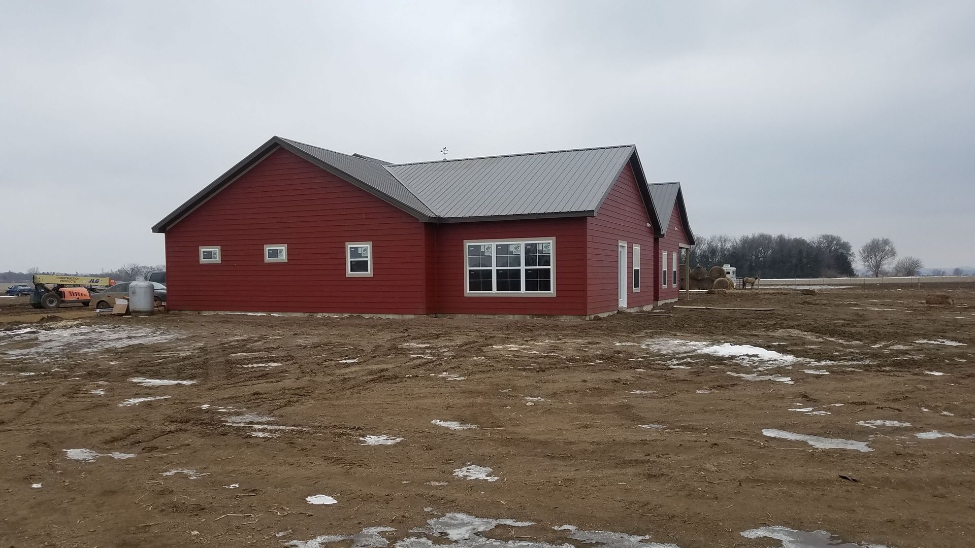 A red house is sitting in the middle of a dirt field.