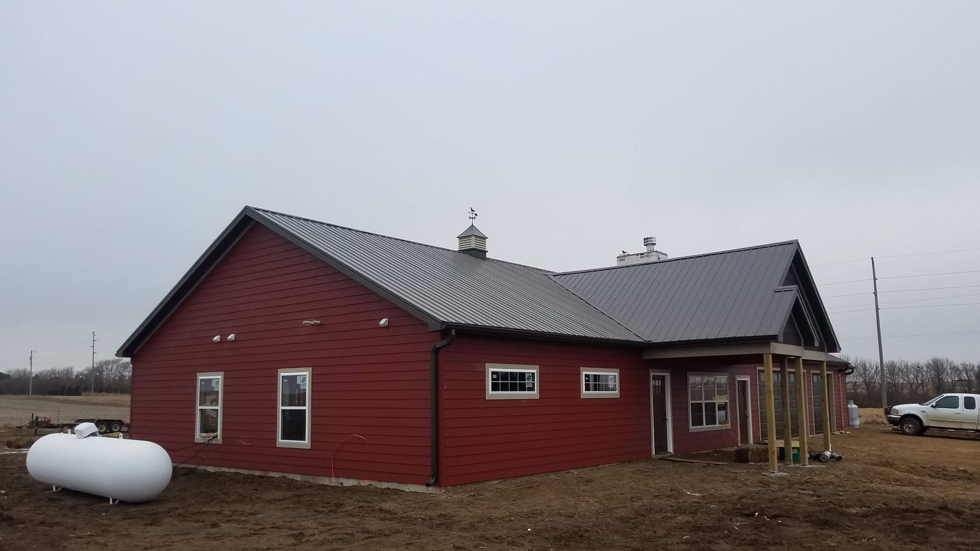 A red house with a propane tank in front of it