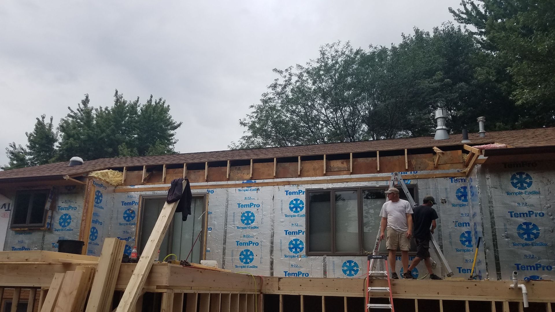 A group of men are working on the roof of a house.