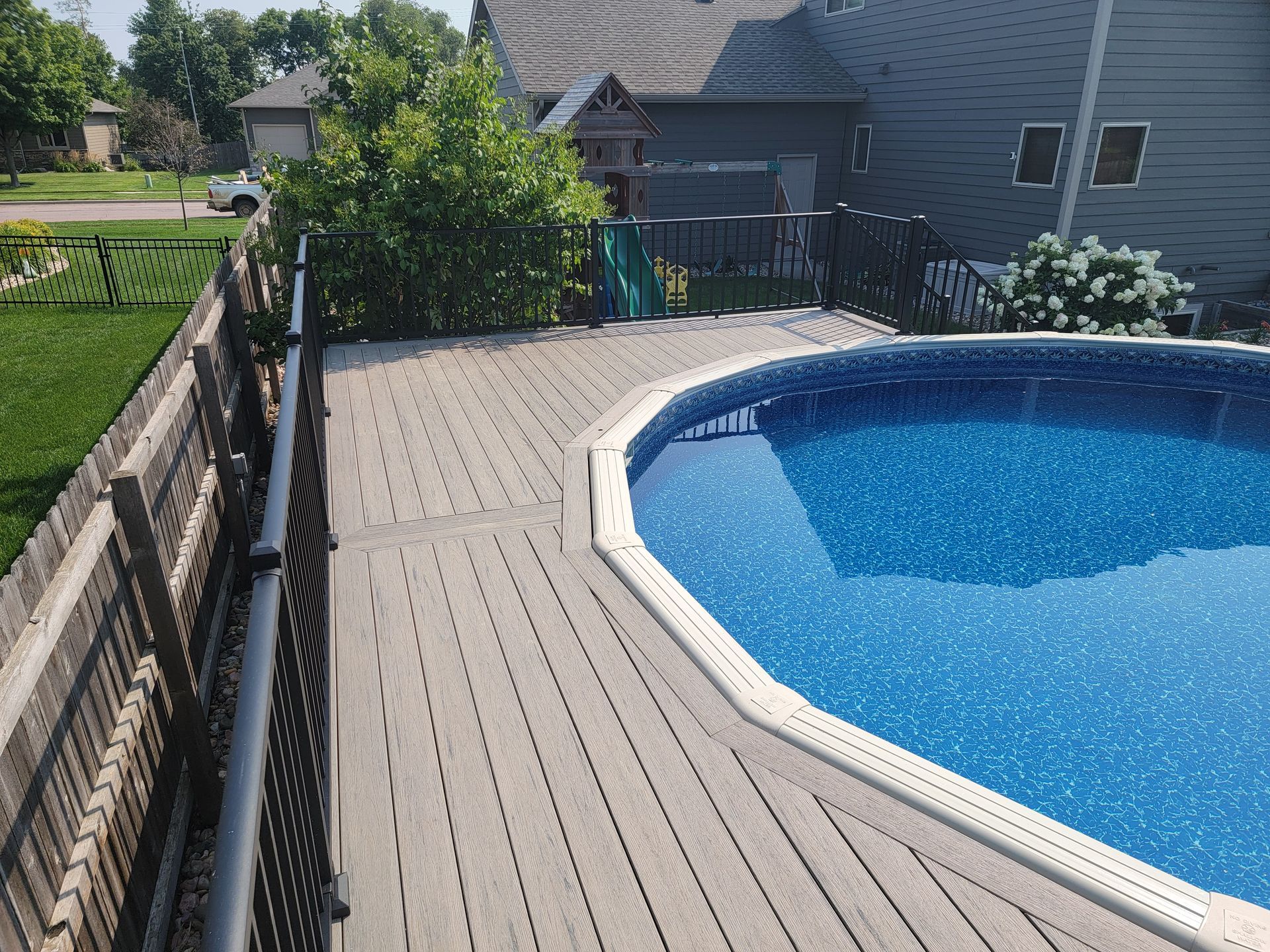 A large swimming pool is surrounded by a wooden deck.