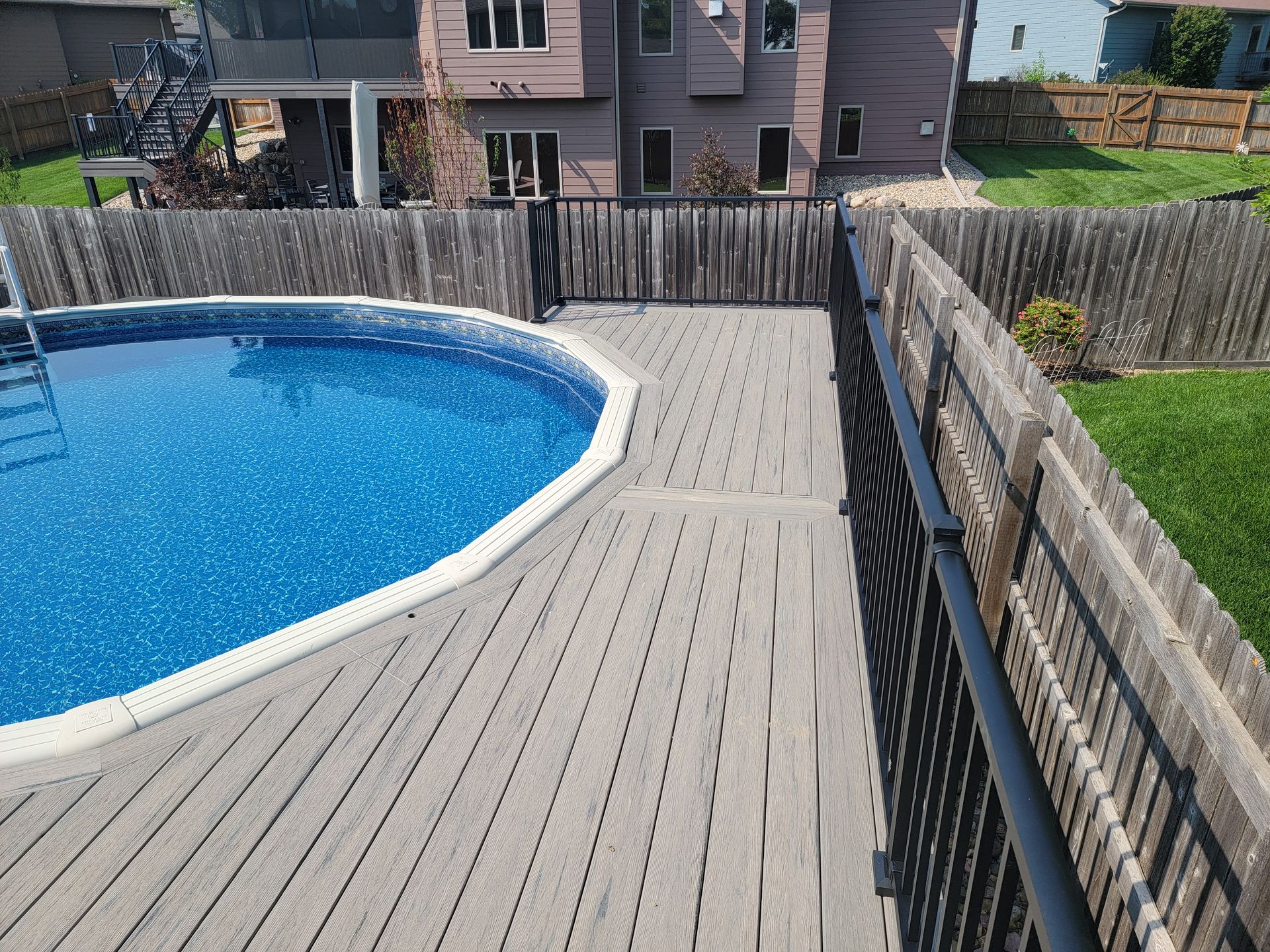A large swimming pool is surrounded by a wooden deck.