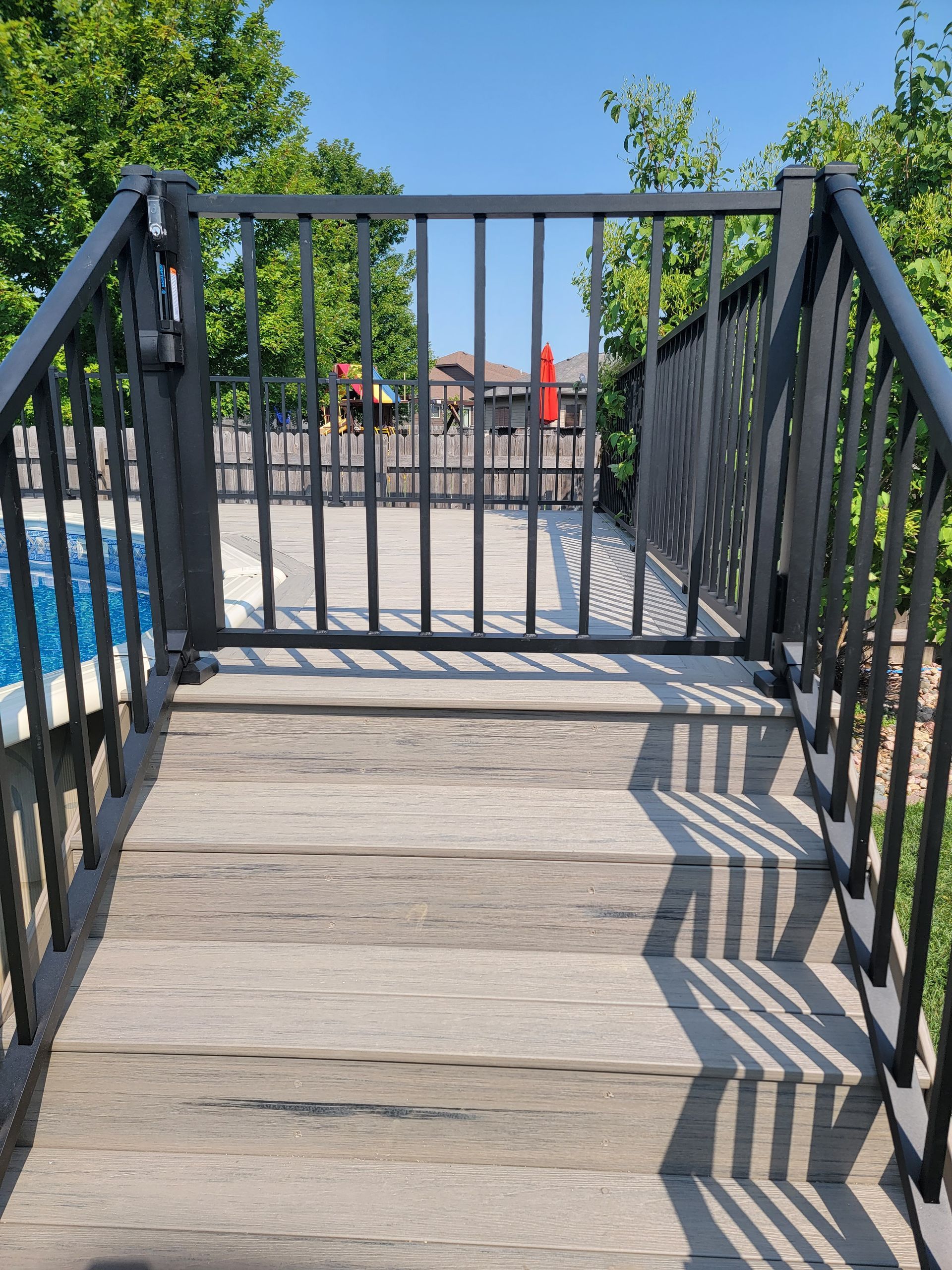 A wooden bridge with a metal railing leading to a pool
