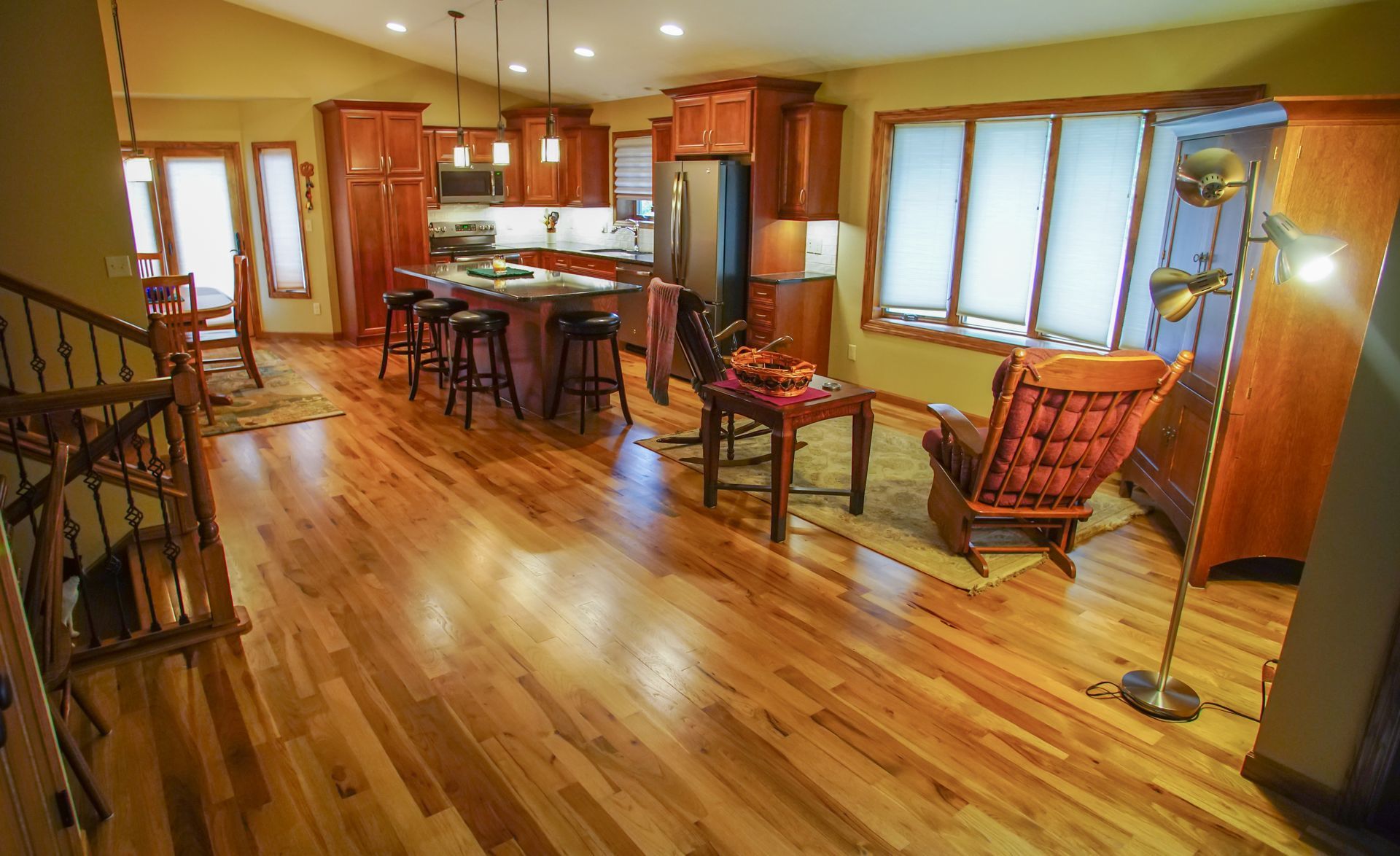 A living room with hardwood floors and a kitchen in the background.