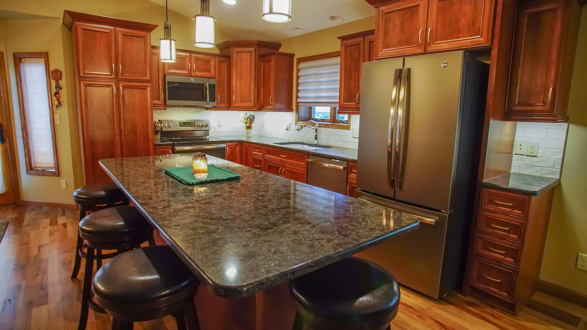A kitchen with wooden cabinets, granite counter tops, stainless steel appliances and a large island.