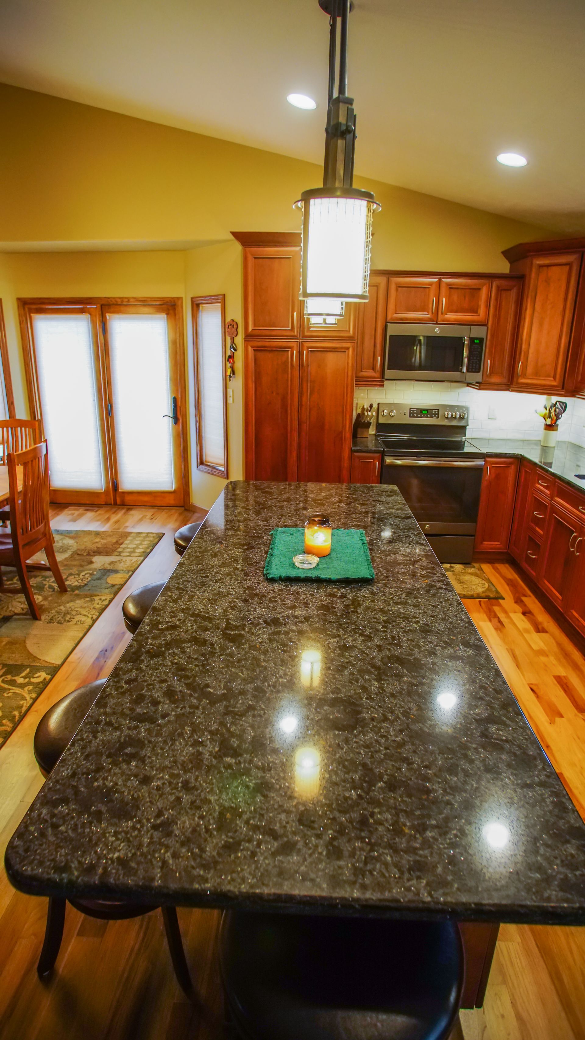 A kitchen with a large granite counter top and wooden cabinets.