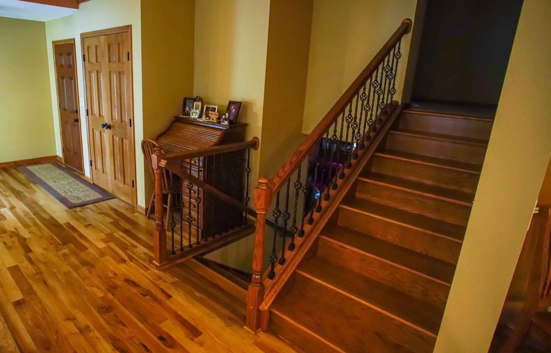A wooden staircase with a wrought iron railing in a house.