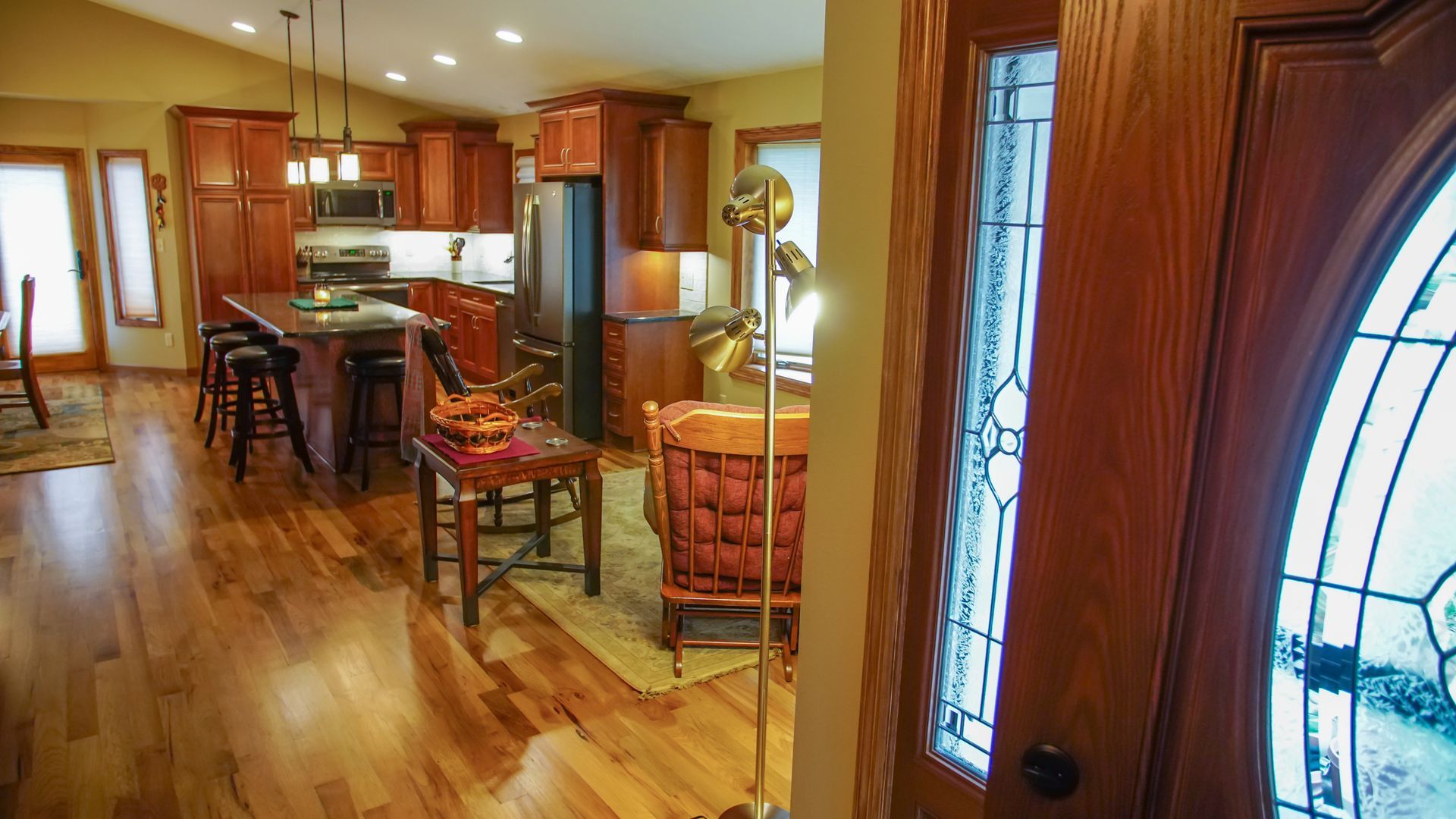 A view of a kitchen and living room from the front door of a house.
