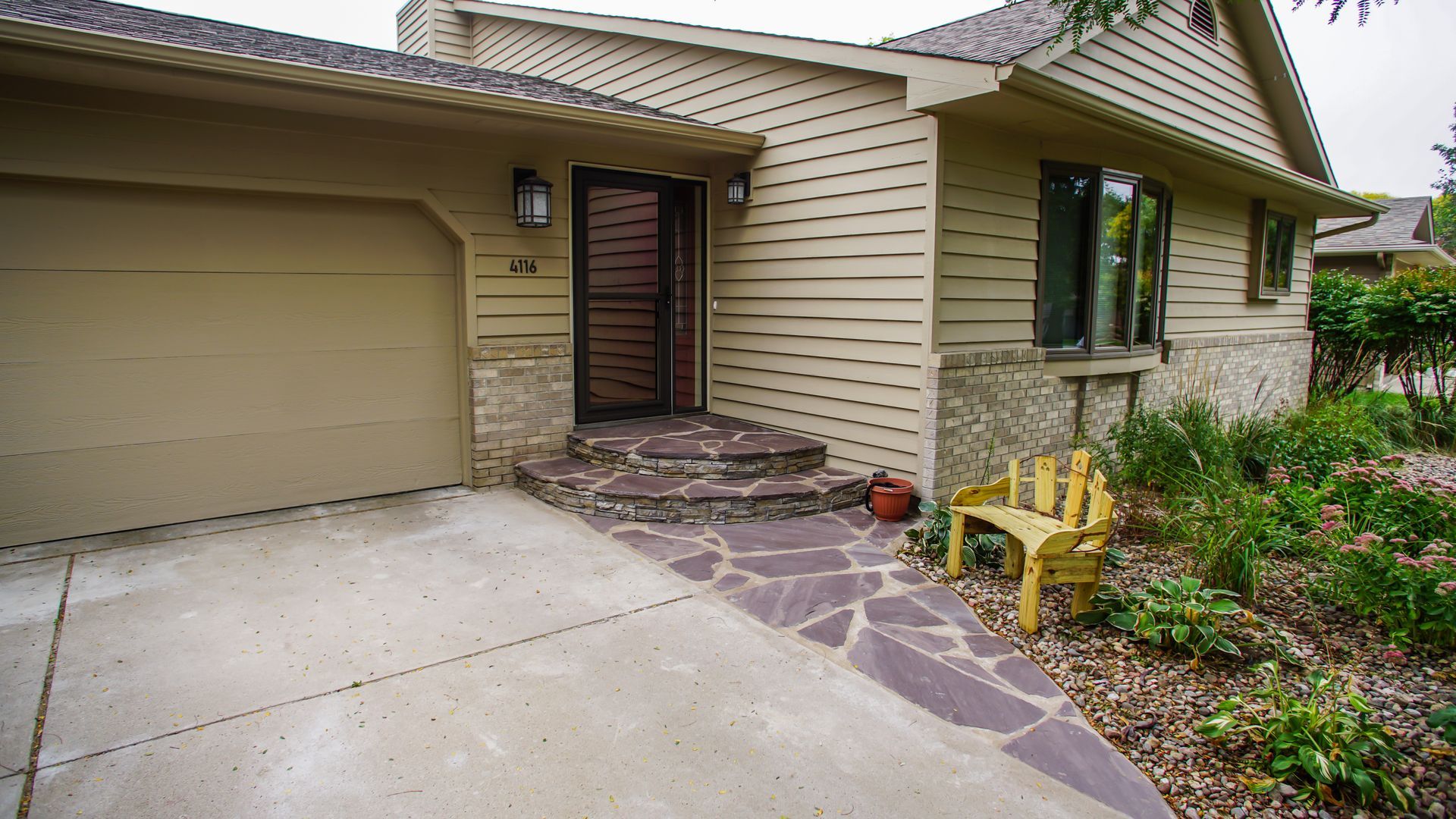 A house with a garage and a yellow chair in front of it.