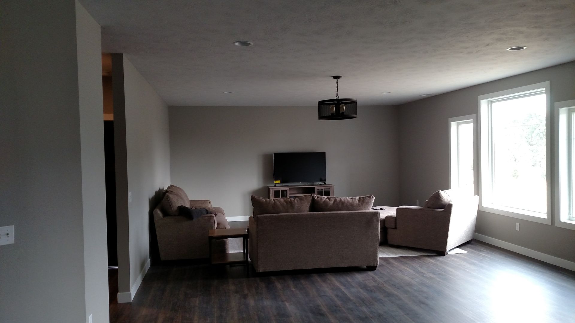 A living room with a couch, chairs and a television.