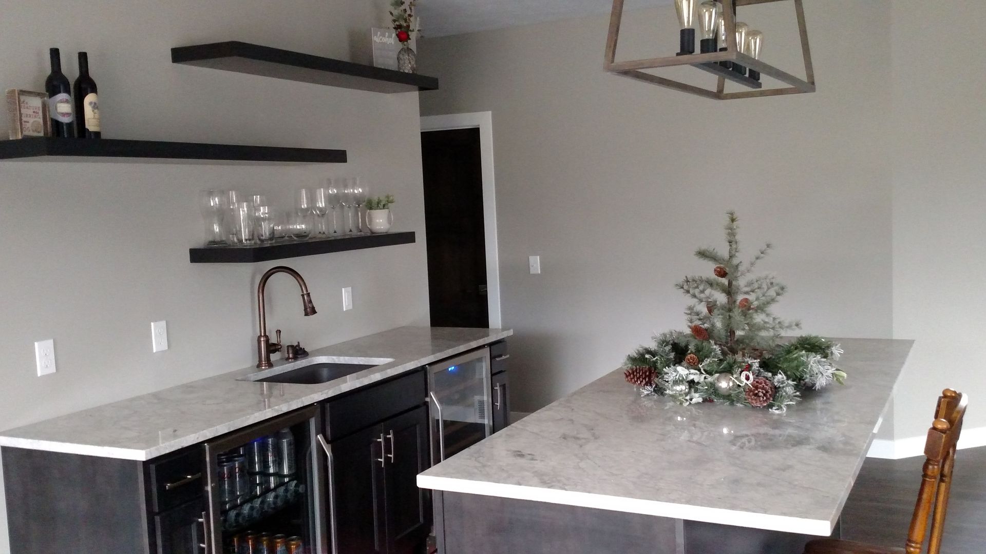 There is a christmas tree in the middle of the kitchen.