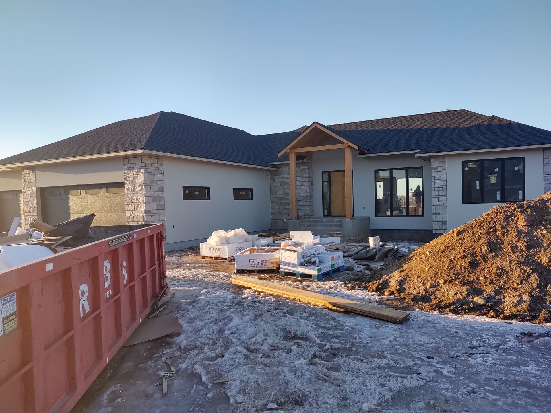 A large house under construction with a large pile of dirt in front of it.