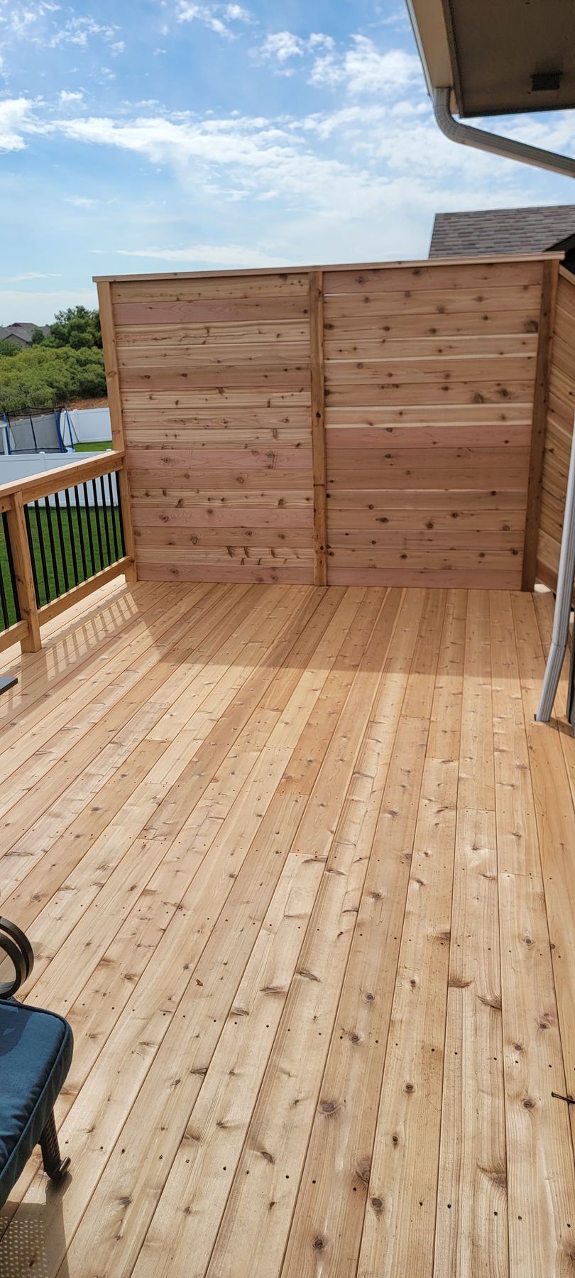 A wooden deck with a fence and a chair on it.
