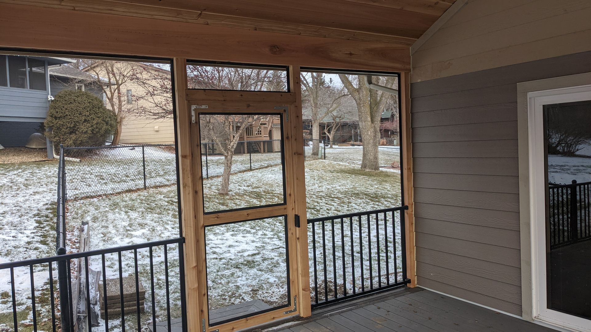 A screened in porch with a view of a snowy yard.