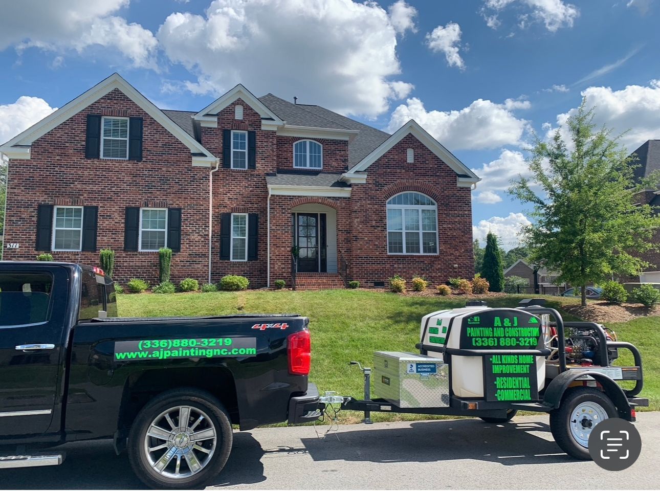 A black truck is parked in front of a large brick house