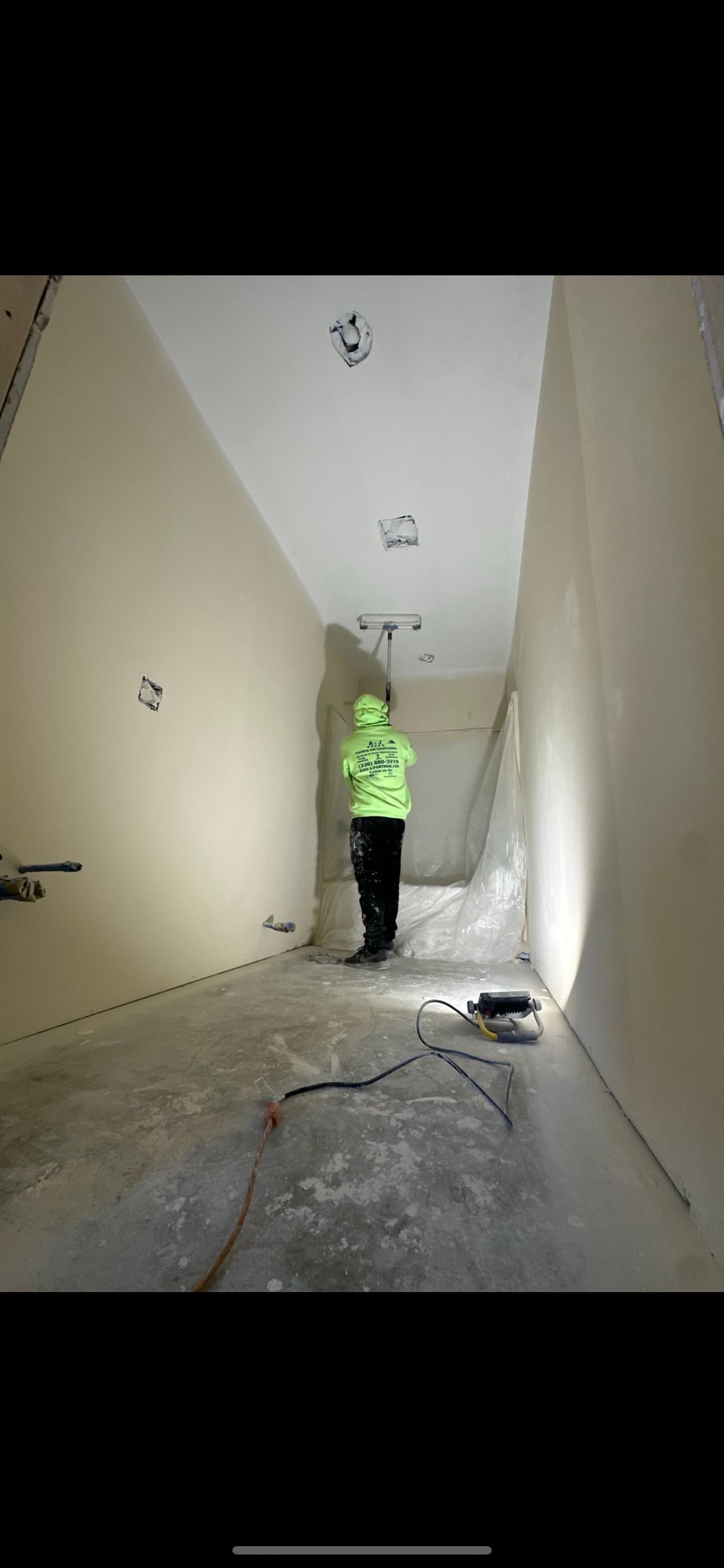 A person in a neon green jacket is walking down a hallway.