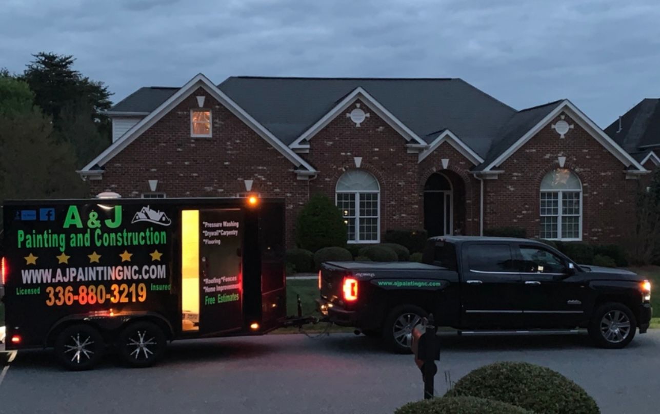 A truck that says a & j painting and construction is parked in front of a house