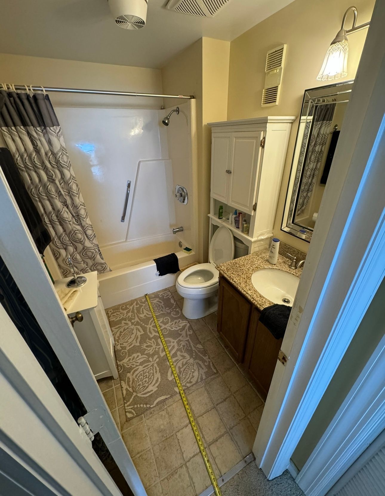 A bathroom with a tub , toilet , sink and mirror.