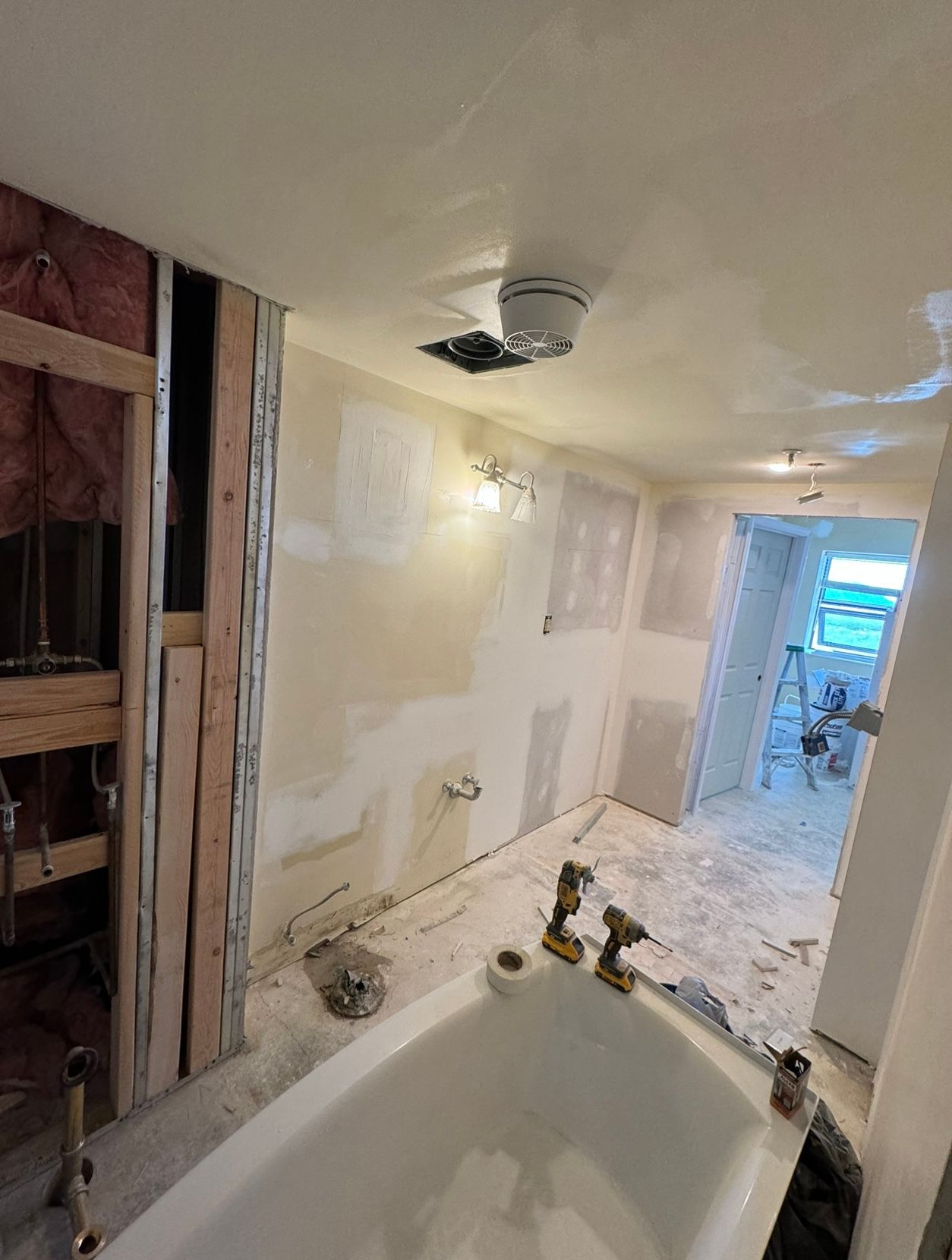 A bathroom under construction with a bathtub and a ceiling fan.
