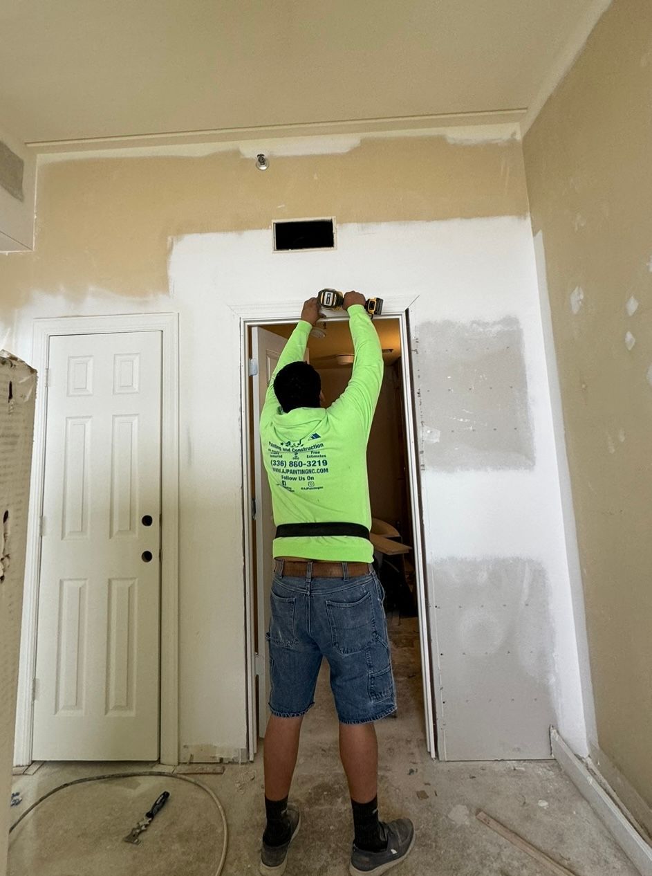 A man in a neon green shirt is working on a doorway.