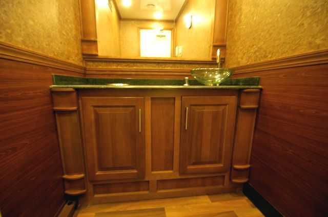 Wooden bathroom vanity with a green countertop and mirror in warm lighting