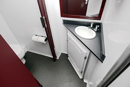 Compact restroom with toilet, sink, and paper towel dispenser on patterned floor.