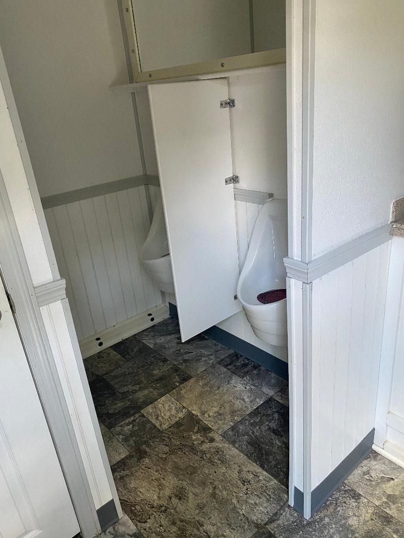 Small bathroom with an open cabinet, white walls, and a tiled floor.