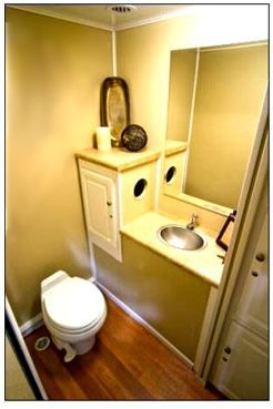 Tiny bathroom with wall-mounted sink, mirror, and toilet under a vanity shelf.