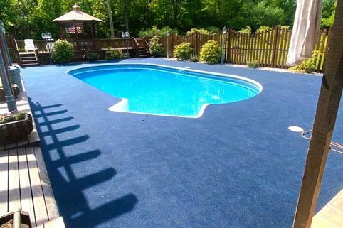 A large swimming pool is surrounded by a fence and a deck.