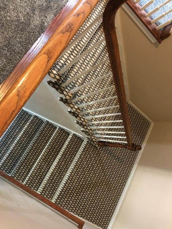 A staircase with a wooden railing and a carpeted floor.