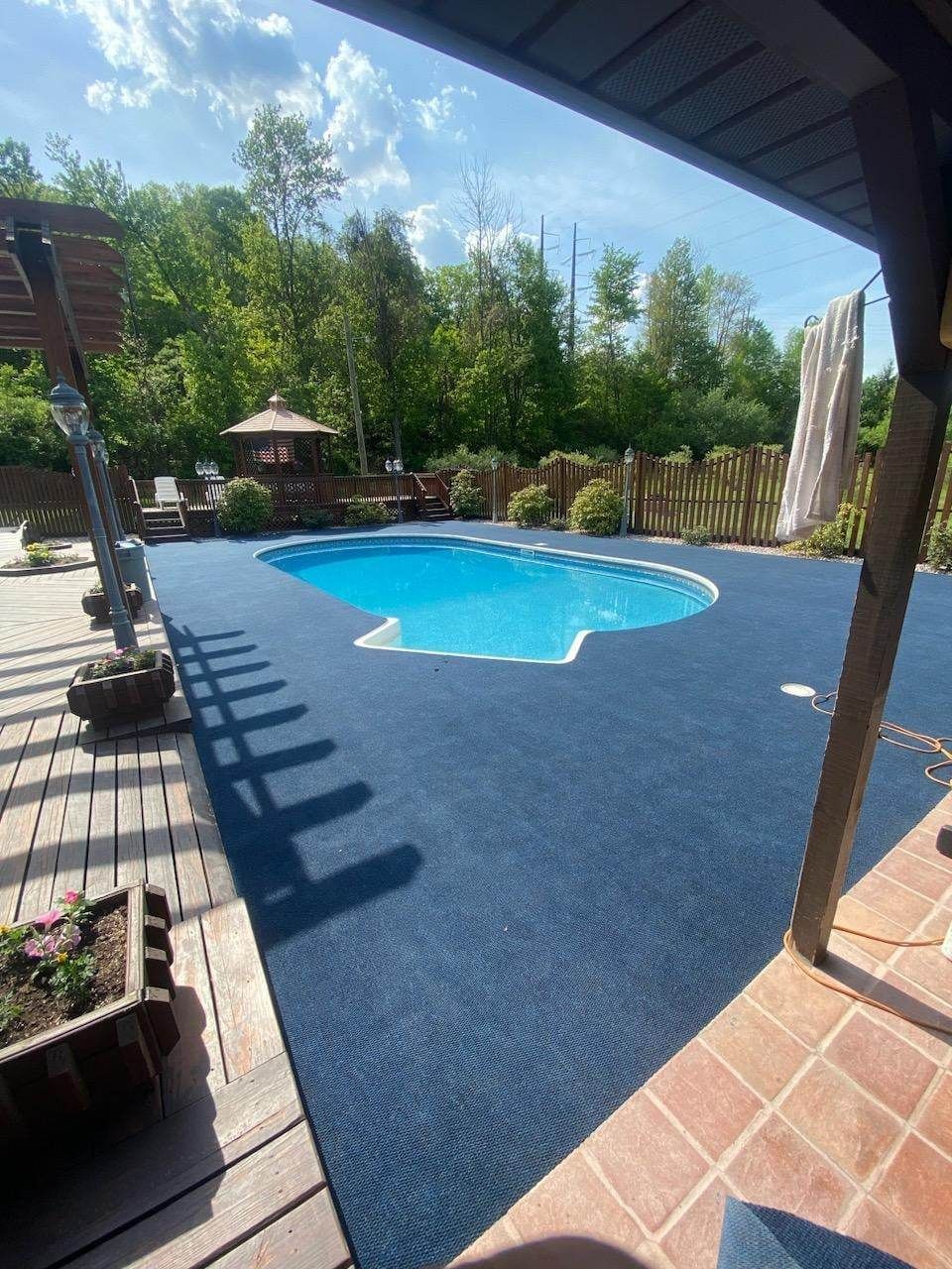 A large swimming pool is surrounded by trees and a deck.