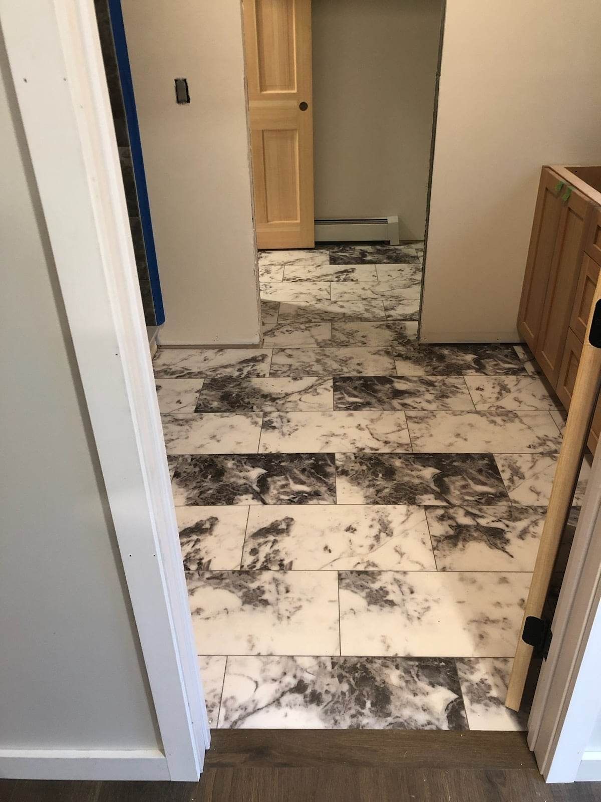 A hallway with marble tiles on the floor and a wooden cabinet.