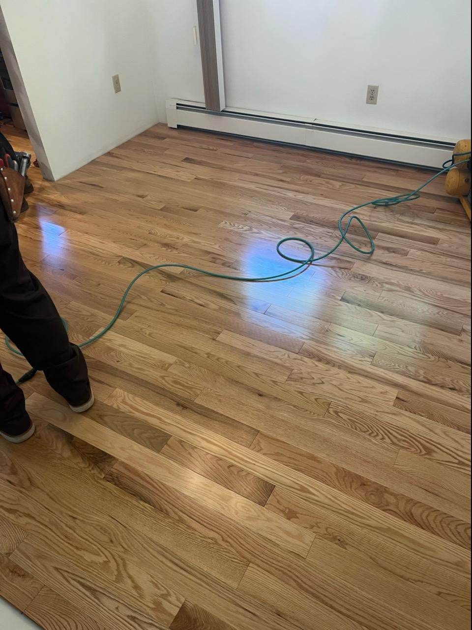 A person is standing on a wooden floor in a room.