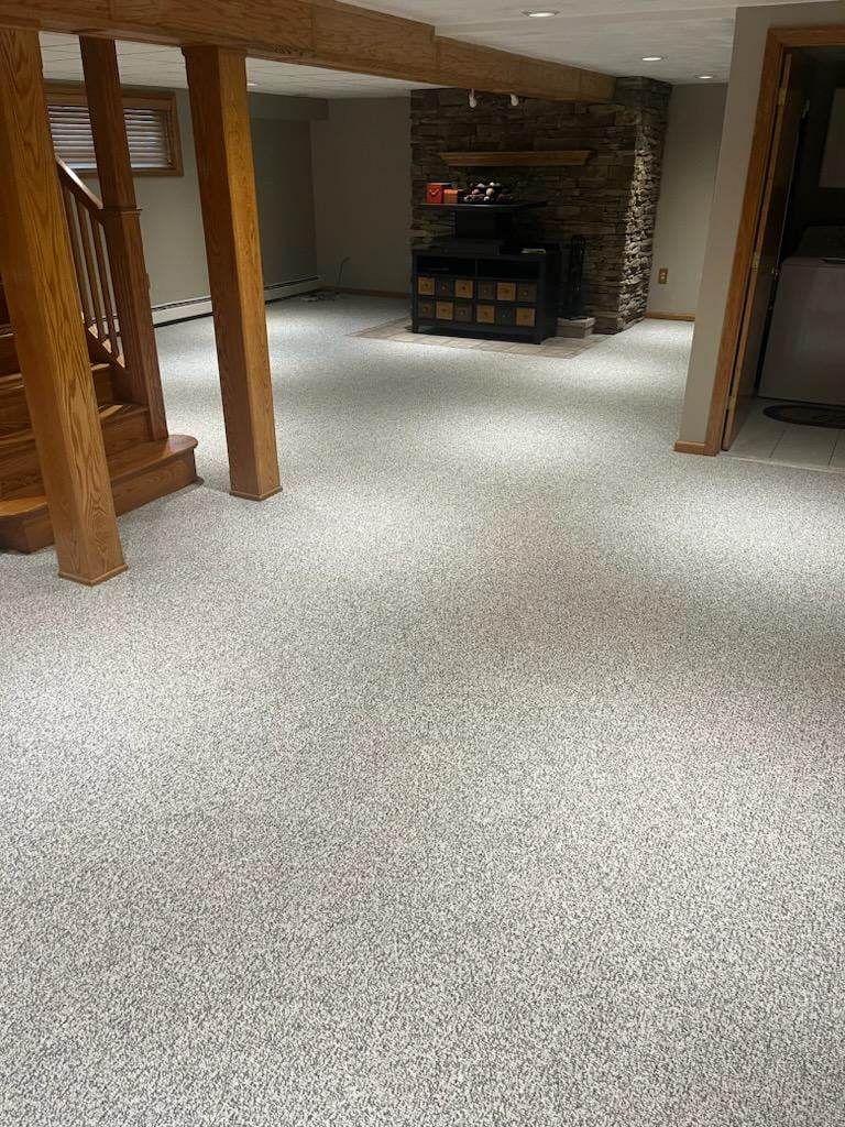 A basement with a carpeted floor and a fireplace.