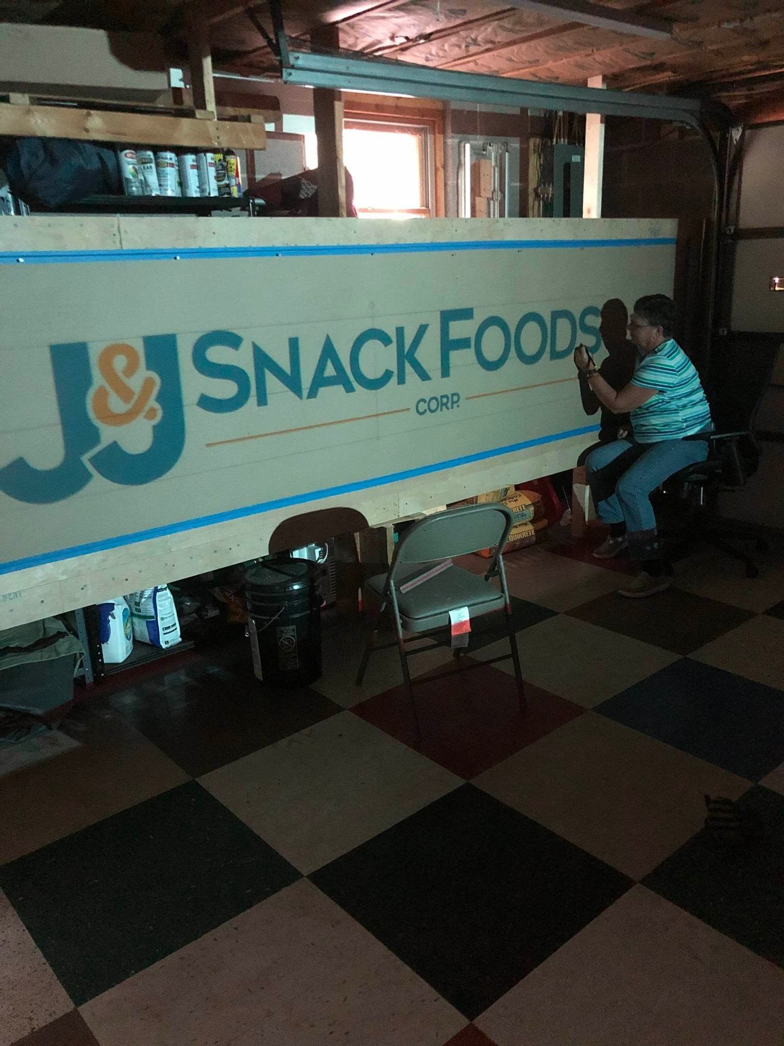 A man is sitting in front of a snack foods truck