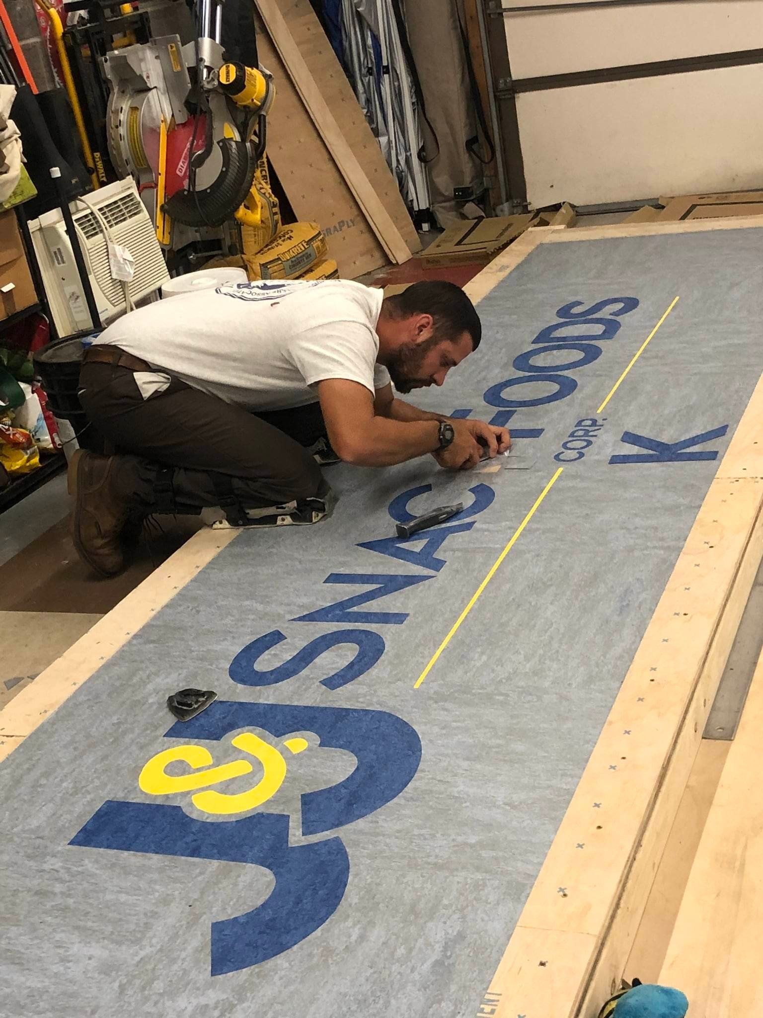 A man is kneeling down in front of a large sign.