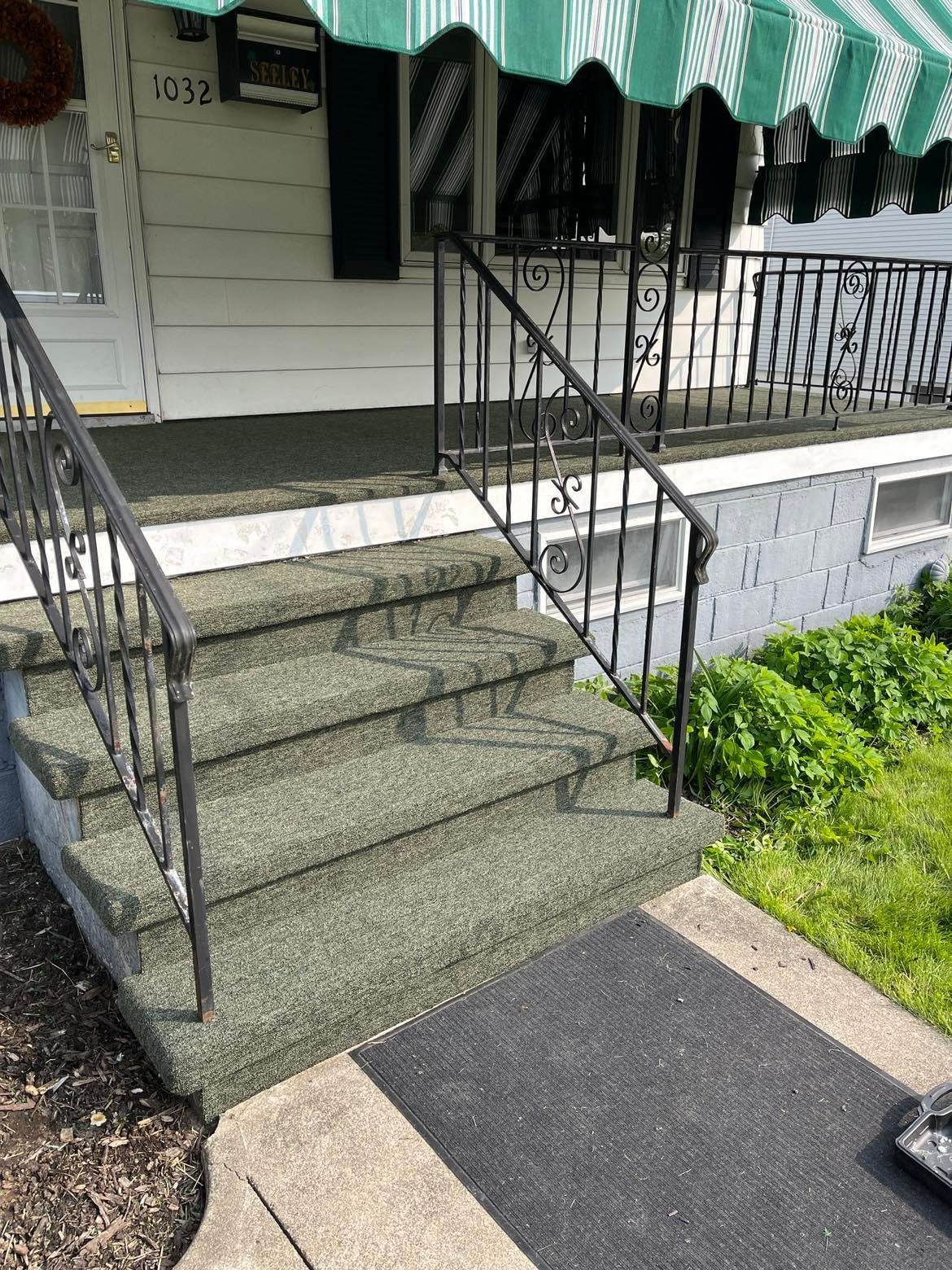 A set of stairs leading up to a porch with a green and white awning.