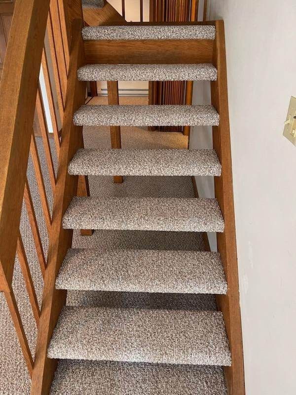 A wooden staircase with carpeted steps and a wooden railing.