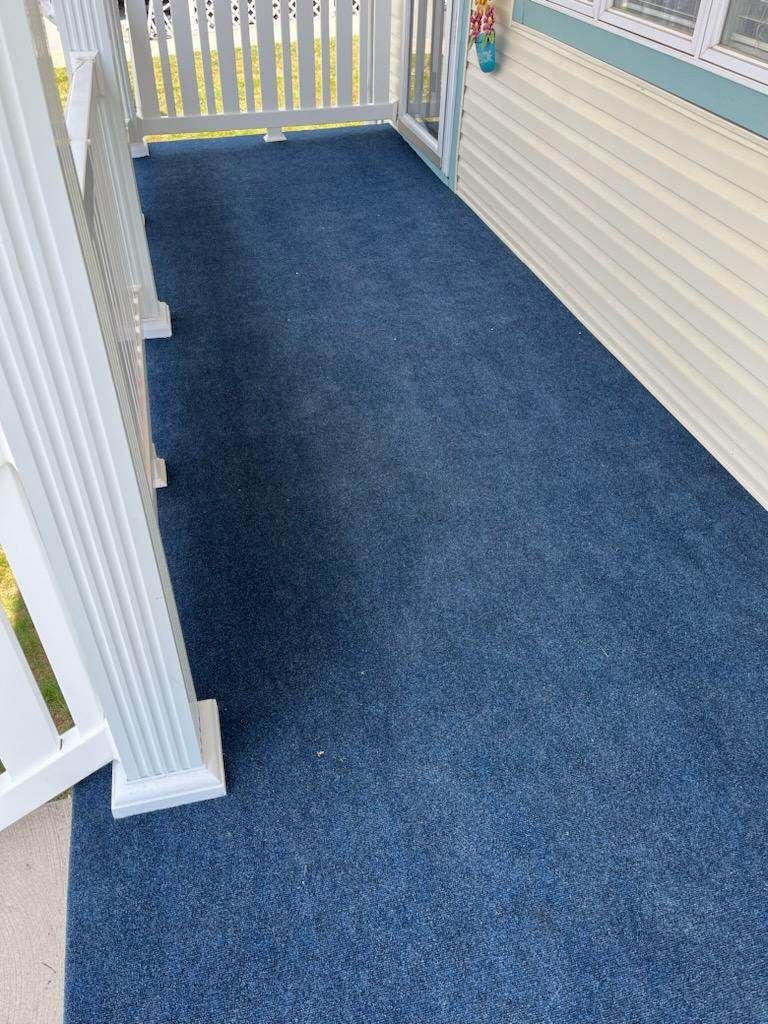 There is a blue carpet on the porch of a house.