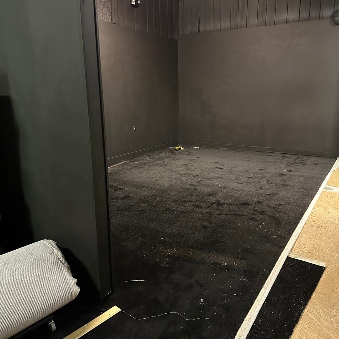 A room with a black wall and a white towel on the floor.