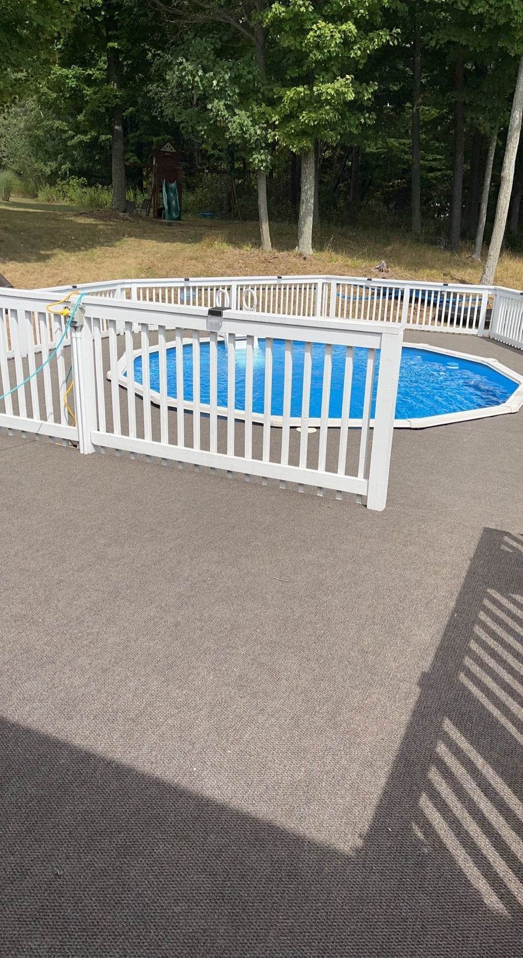 A large swimming pool surrounded by a white fence in a backyard.