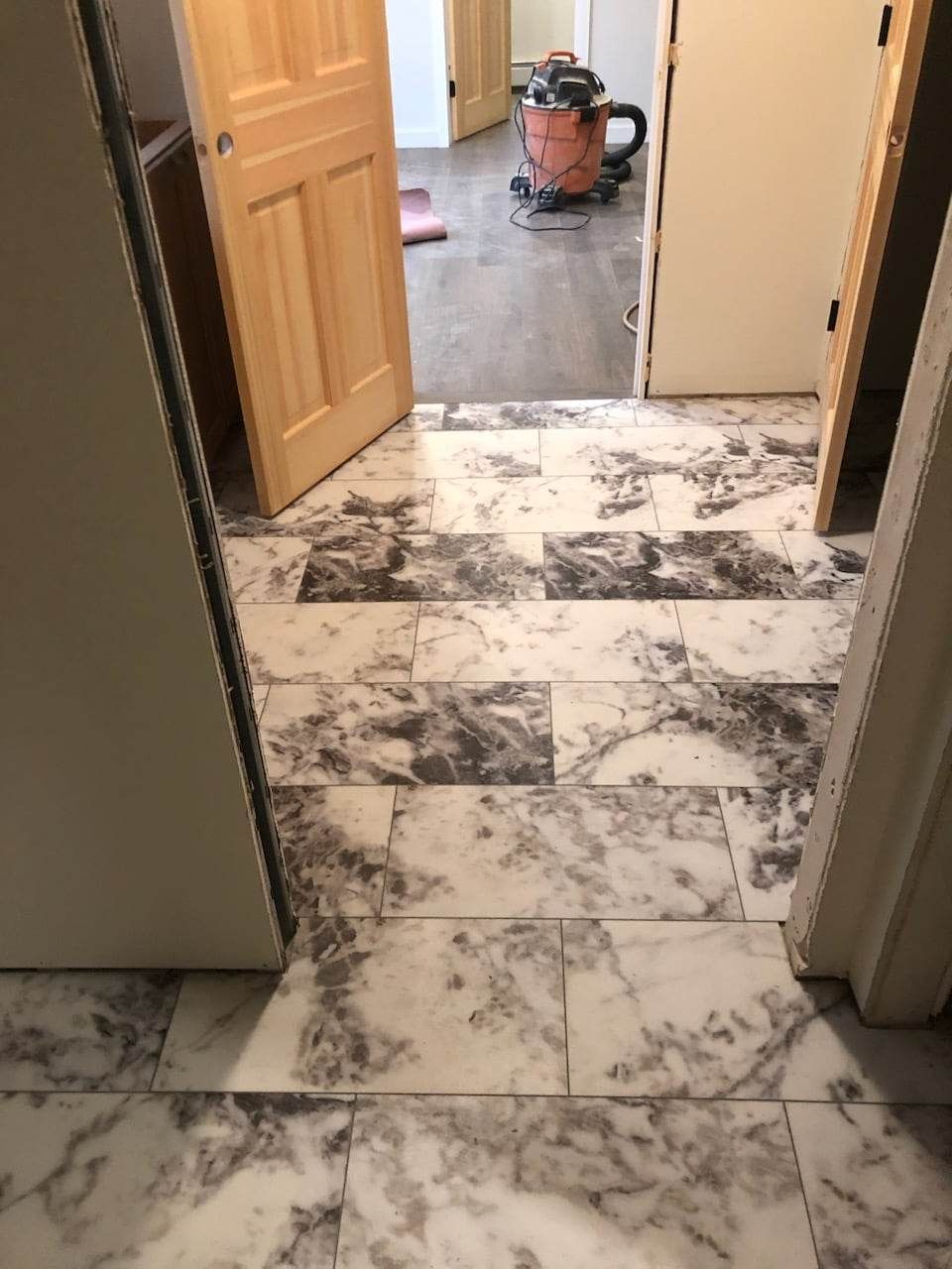 A vacuum cleaner is sitting on a marble floor in a hallway.