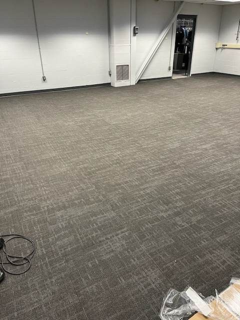 A large empty room with a carpeted floor and white walls.