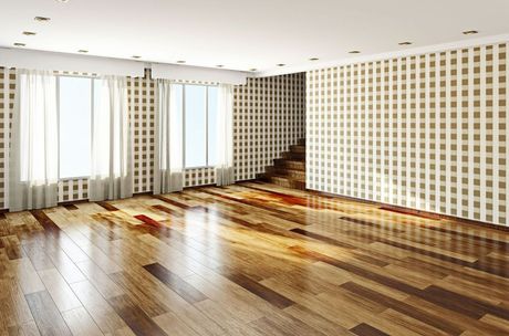 An empty room with wooden floors and checkered wallpaper