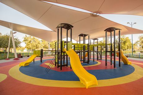 A colorful playground with a yellow slide in the middle of it.